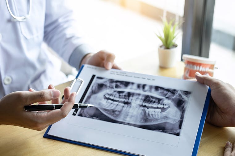 Image of doctor or dentist presenting with tooth x-ray film recommend patient in the treatment of dental and dentistry, working at workplace.